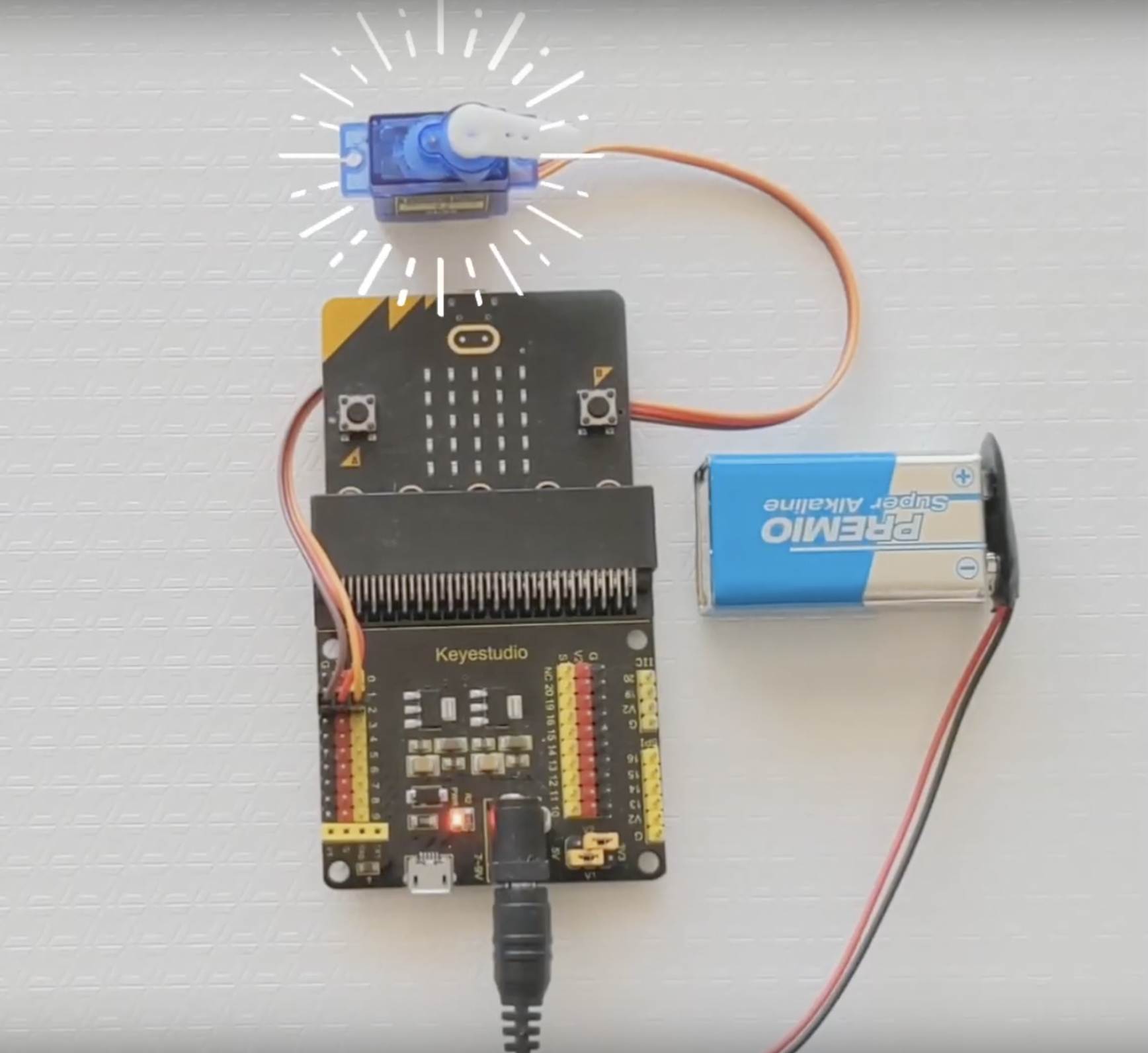 Imagen que muestra las conexiones entre la placa micro:bit, un servomotor y un portador de pilas