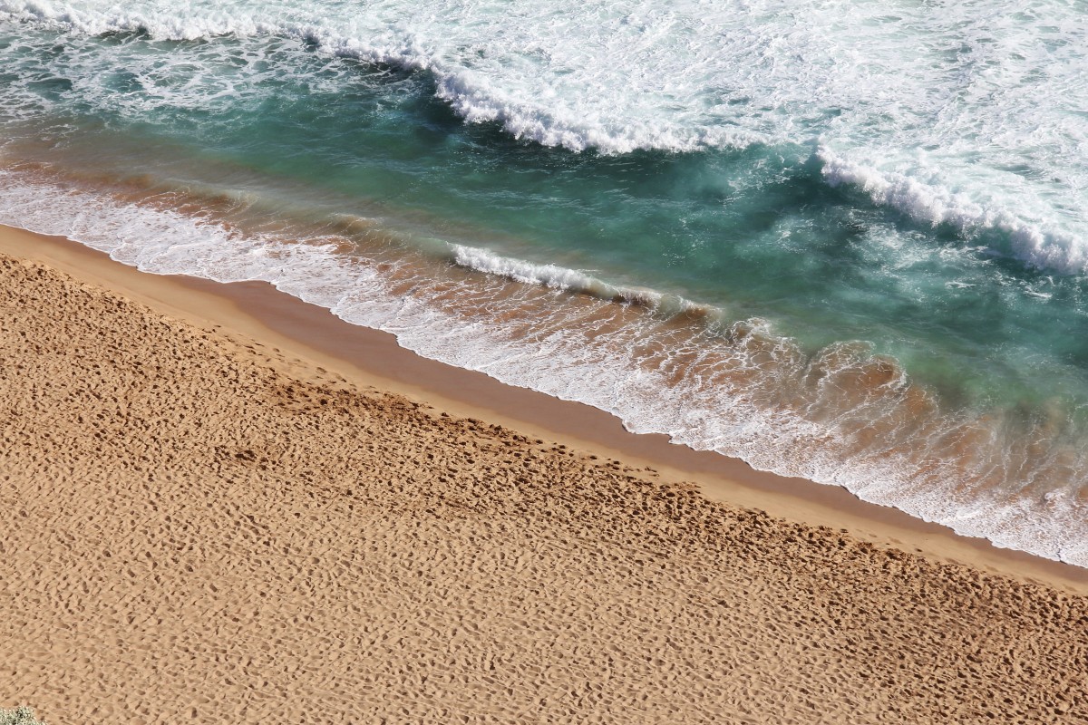 En la imagen puedes ver la orilla del mar con algunas olas y arena