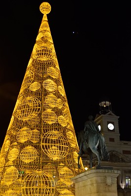 Foto noctura del la Puerta del Sol de Madrid con un gran árbol de navidad de luz dorada.