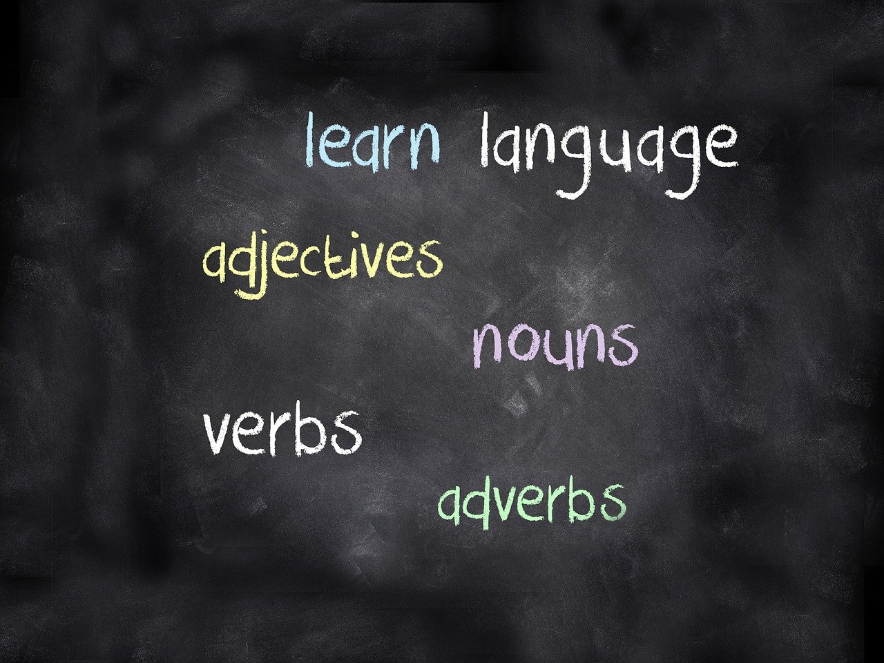 Pizarra con las palabras "learn" "language" "nouns" "adjetives" "verbs" y "adverbs" escrita