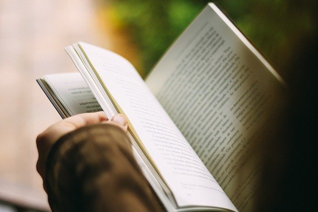 La fotografía de un libro abierto entre las manos de alguien.