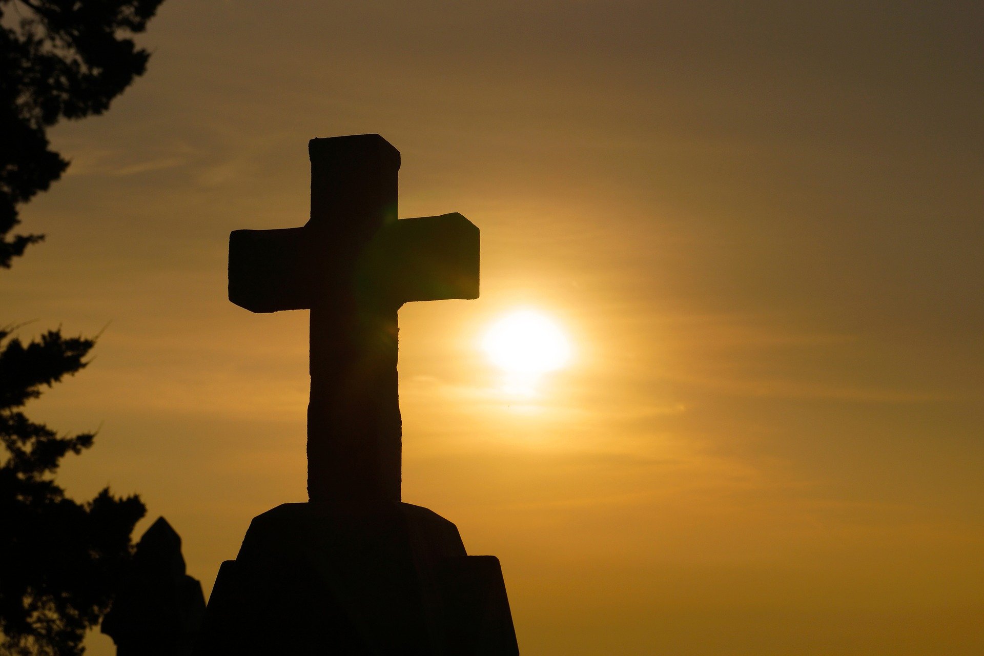 Cruz de piedra con el sol de fondo