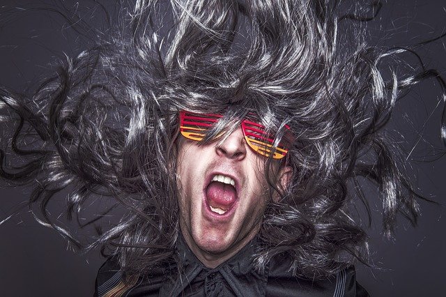 Un hombre conpeluja y gafas falsas de colores grita con la melena al viento
