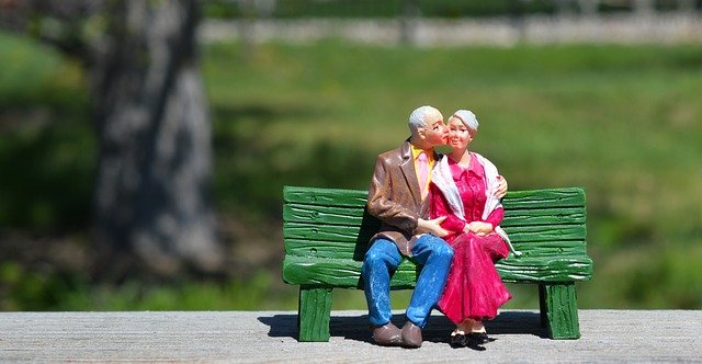 Fotografía de una figurita en la que se ve a una pareja de adultos mayores besándose en un banco