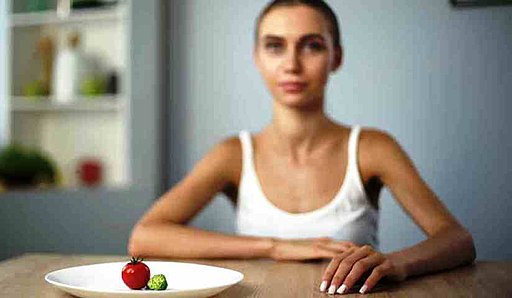 Fotografía de una mujer delgada ante un plato de comida